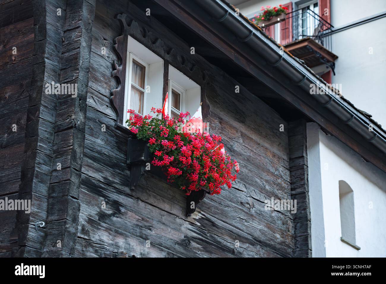 Vibrant Red Flowers on balcony windows in European alpine style, Zermatt, Switzerland Stock Photo