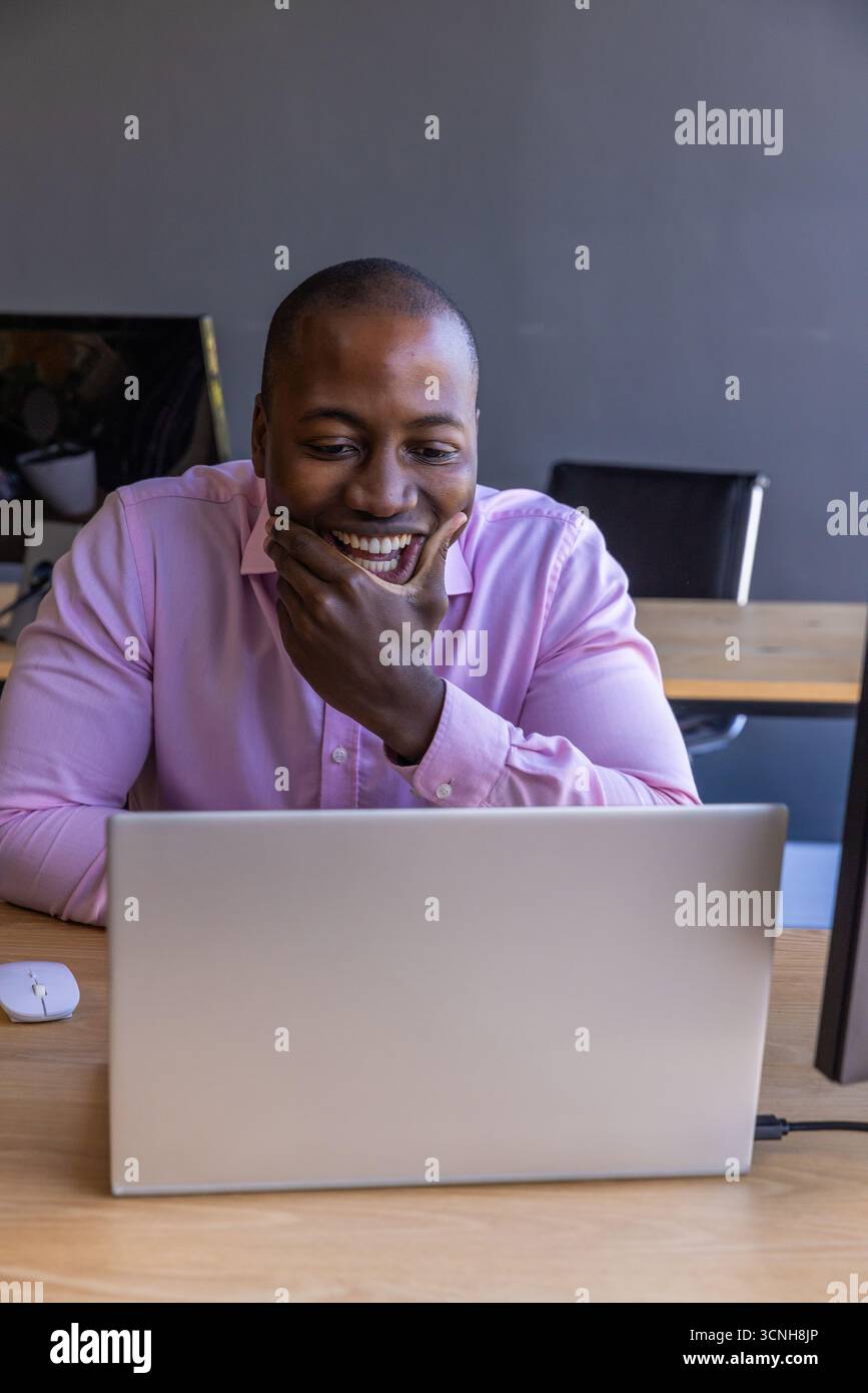 African american man sitting at light wood desk in modern office using ...