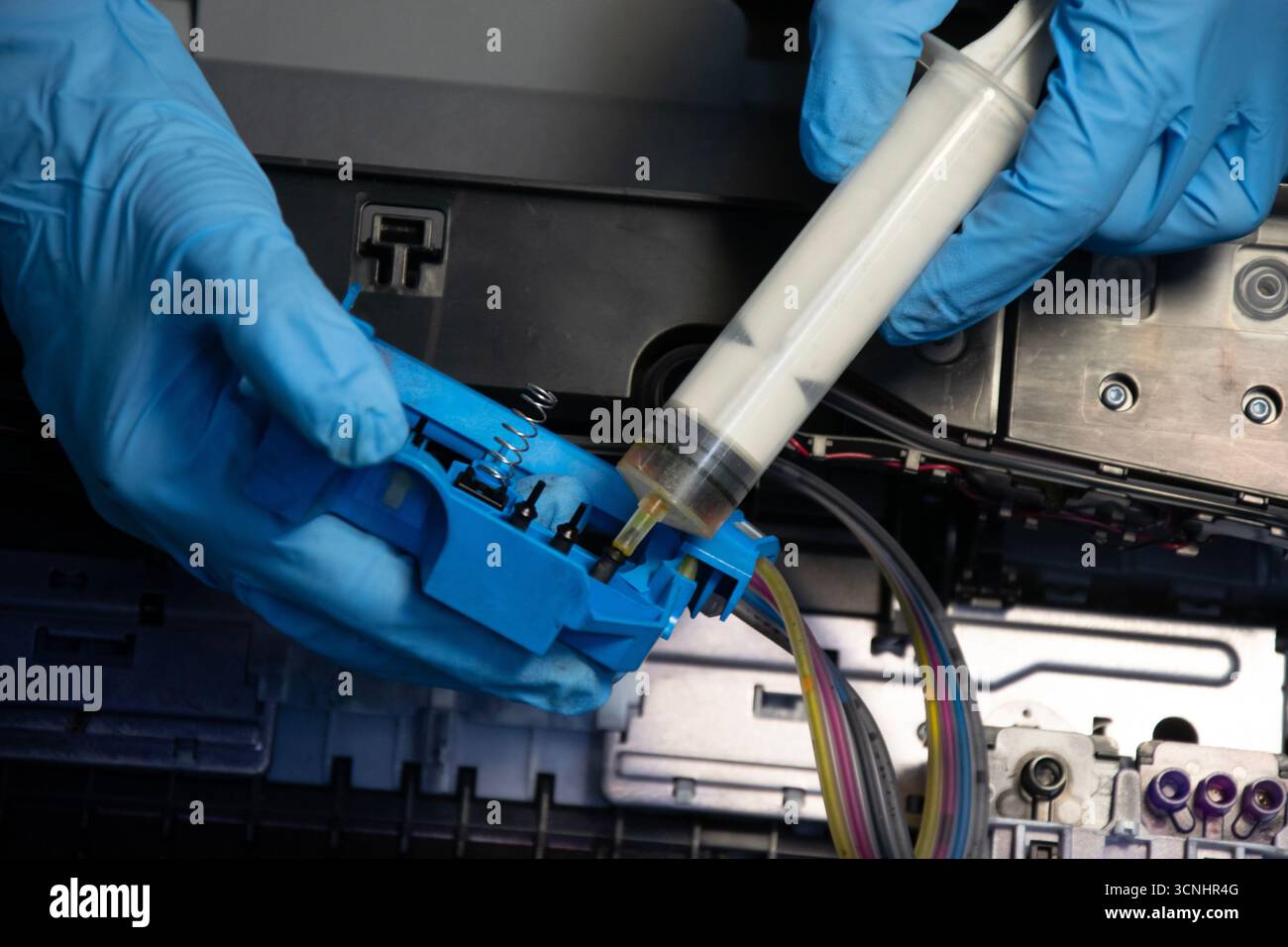 Top view of a technician using a vacuum cleaner to suck ink from a printer. Stock Photo