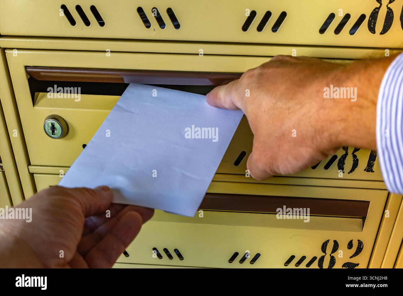 A man takes a letter out of a mailbox, a man puts a letter into a ...