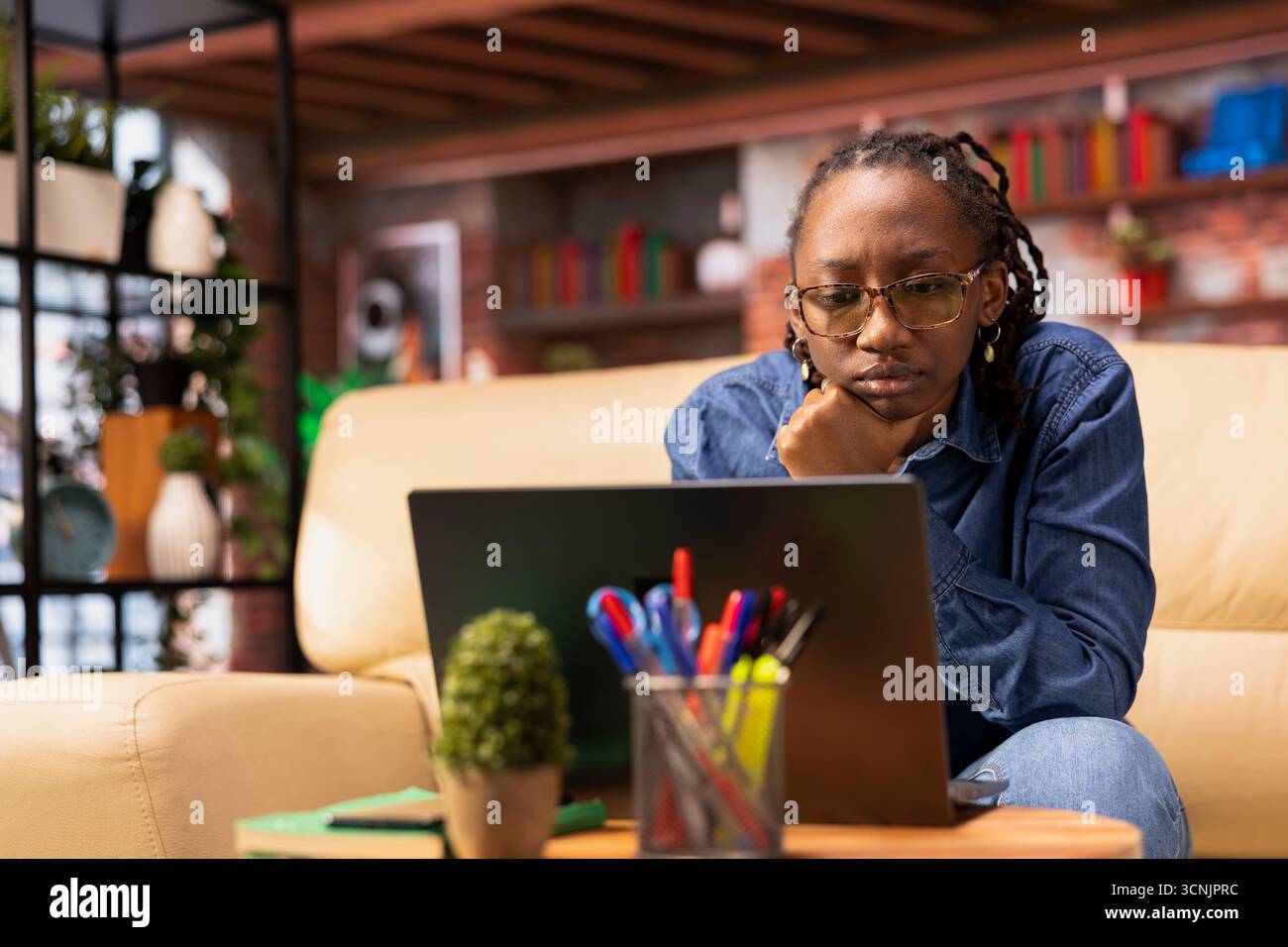 Independent woman using laptop for remote job tasks at home office, doing research and enjoying the benefits of schedule flexibility. Embracing the modern lifestyle of freelance work. Stock Photo