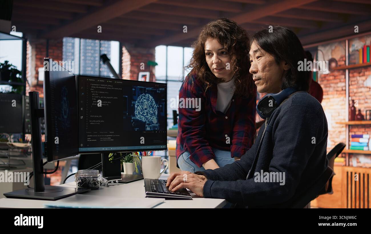 Coworkers collaborating in AI tech agency providing software development services. Teamworking startup office colleagues using artificial intelligence to streamline coding process, camera A Stock Photo