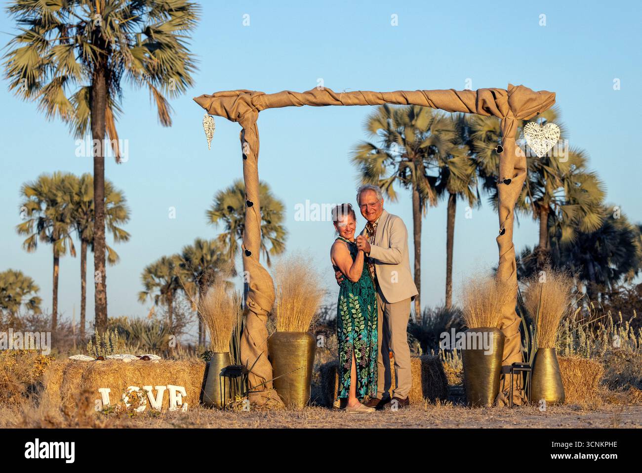 Wedding couple under a wedding arbor in the Makalani palm forest - Onguma Nature Reserve, Namibia, Africa Stock Photo