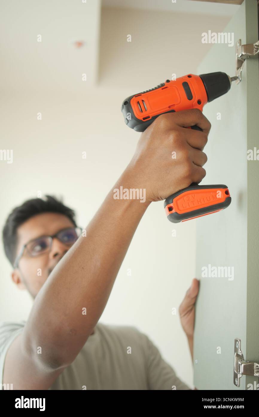 Man using a power drill to install cabinet hardware Stock Photo