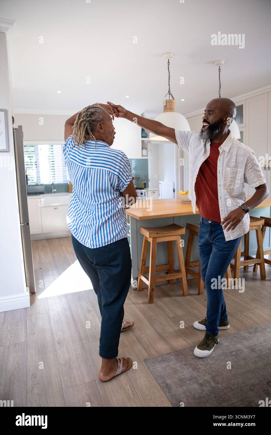 Senior African American couple dancing together in kitchen by island ...