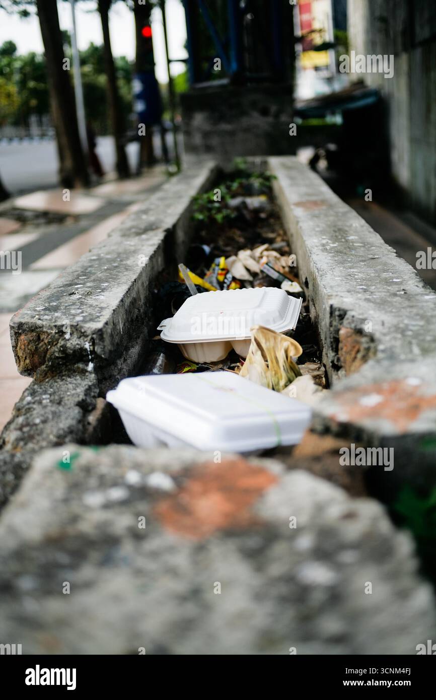 discarded disposable styrofoam lunch box on drainage Stock Photo