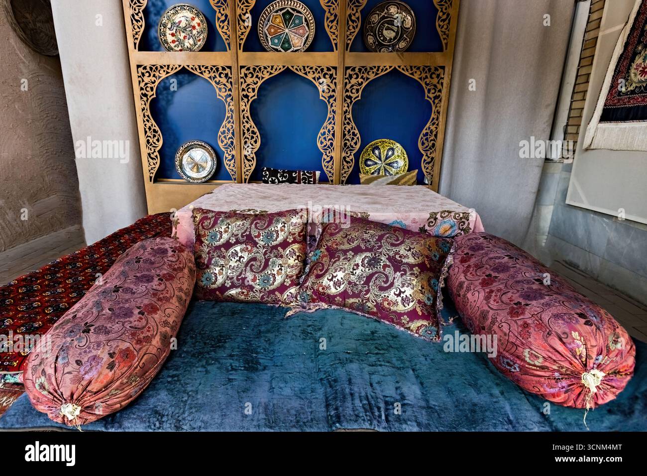 Traditional Uzbek seating area with decorative pillows and ceramic plates on display, reflecting the rich cultural heritage and artistry of Uzbekistan Stock Photo