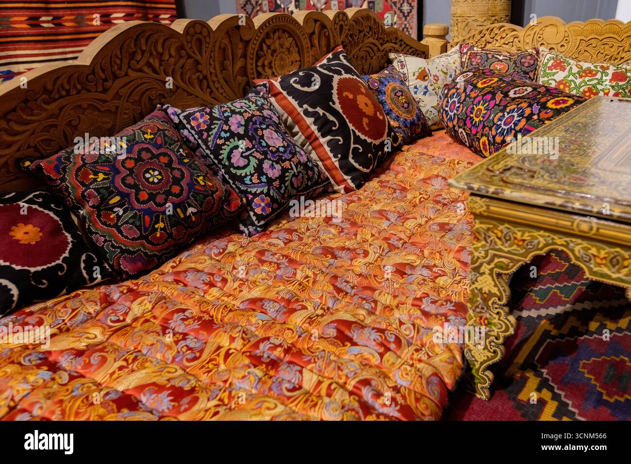 Traditional Uzbek seating area with decorative pillows and ceramic plates on display, reflecting the rich cultural heritage and artistry of Uzbekistan Stock Photo