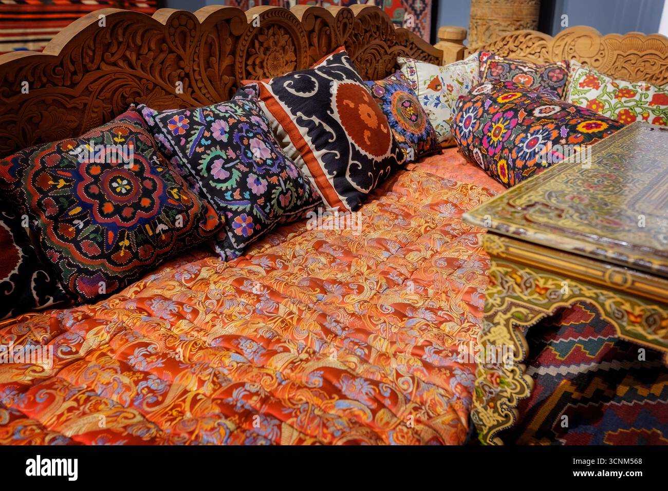 Traditional Uzbek seating area with decorative pillows and ceramic plates on display, reflecting the rich cultural heritage and artistry of Uzbekistan Stock Photo