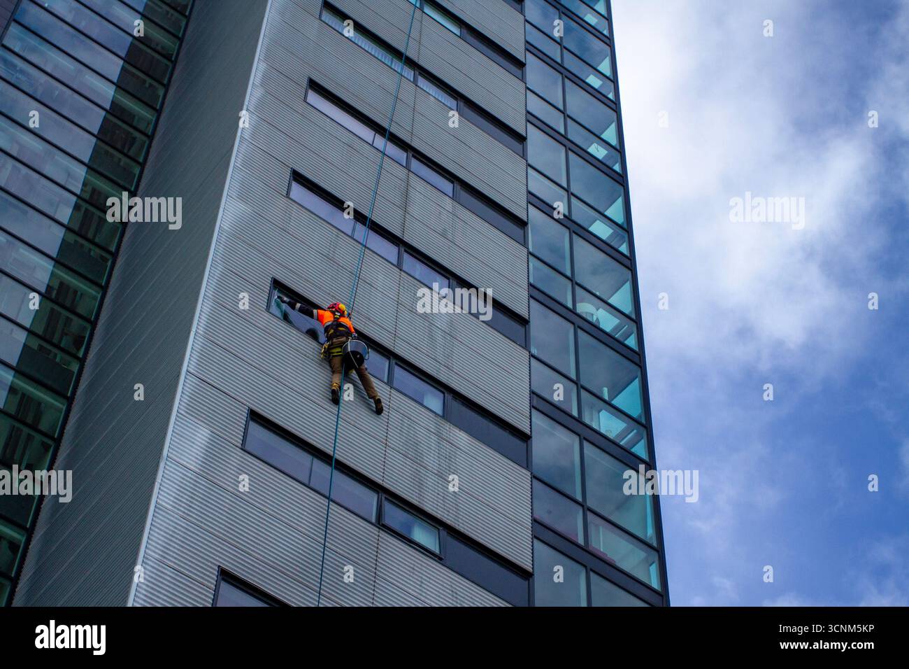 A suspended window cleaner on a high-rise building works from a Bosun's ...