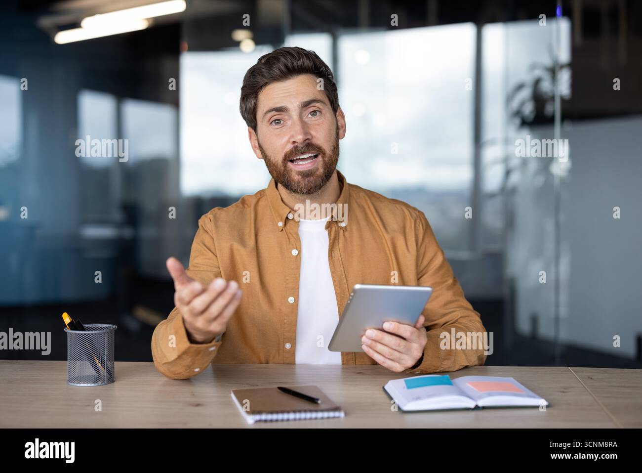 Businessman presenting with a tablet during a virtual meeting ...