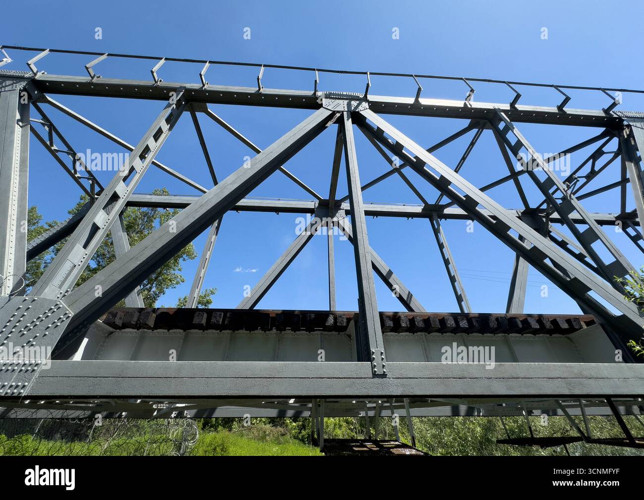 A close-up view of a steel truss bridge shows detailed beams, rivets ...