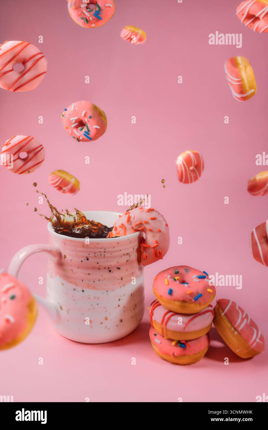 Falling Donuts with Splashing Coffee on Pink Background Stock Photo