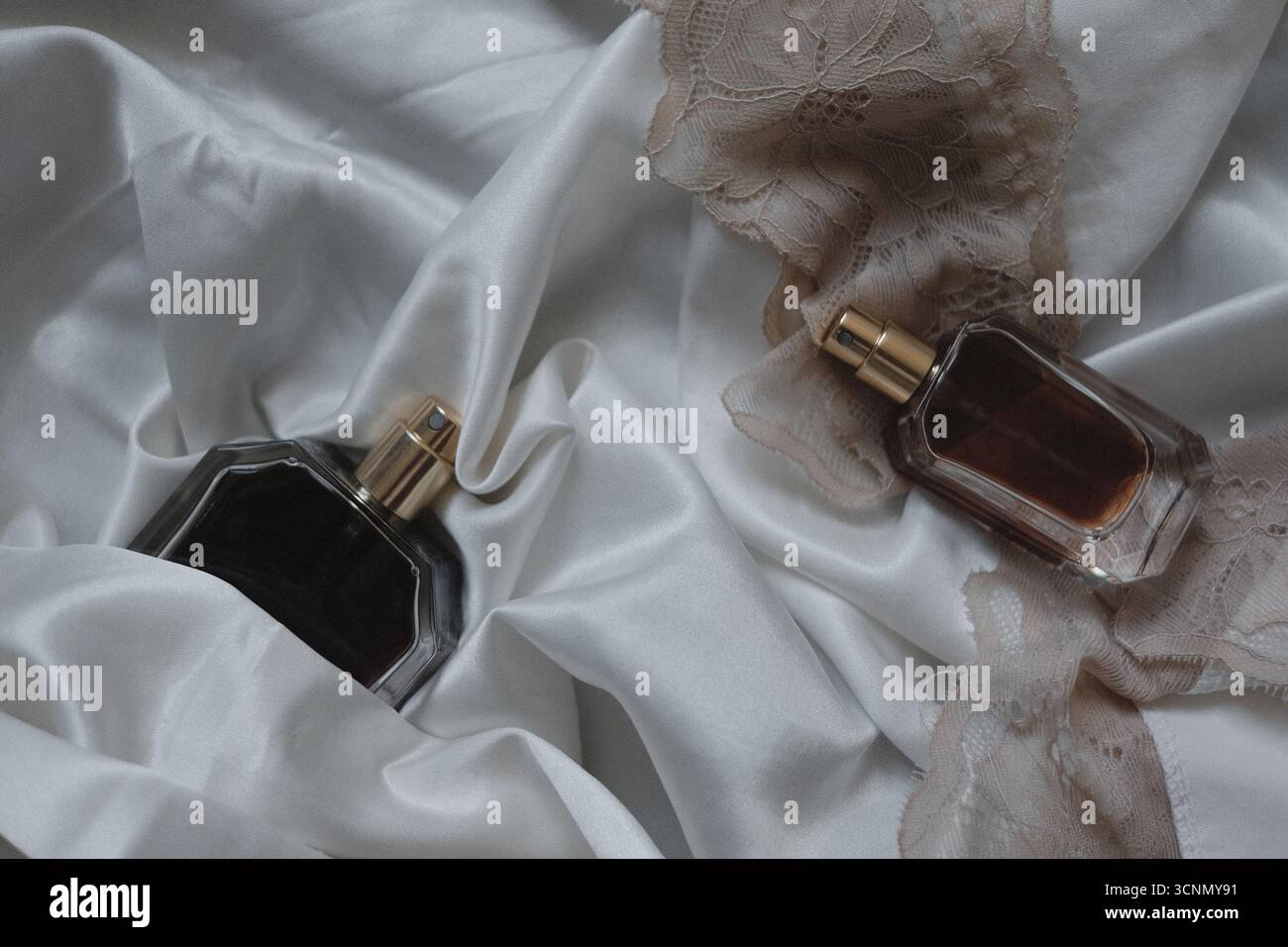 two perfume bottles on white silk background Stock Photo
