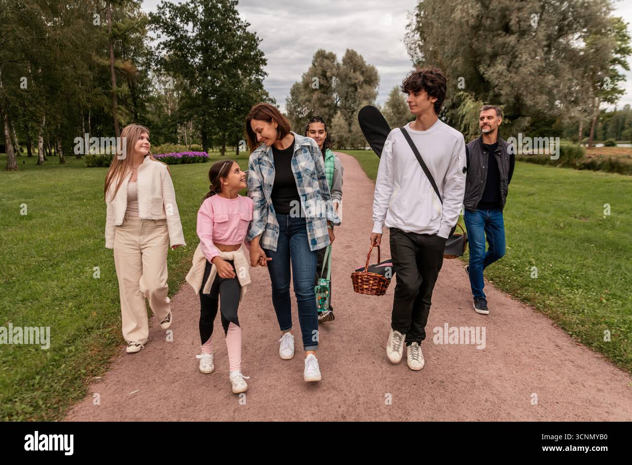 Happy family walking along park path after picnic. Stock Photo