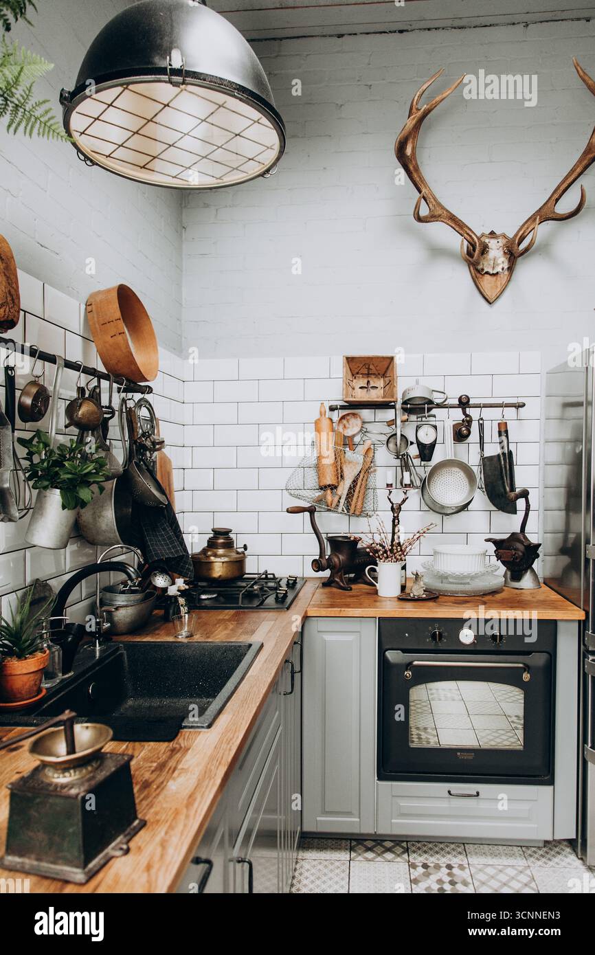 This inviting kitchen features wooden countertops, stylish cookware, and decorative items. The combination of vintage elements with modern appliances Stock Photo