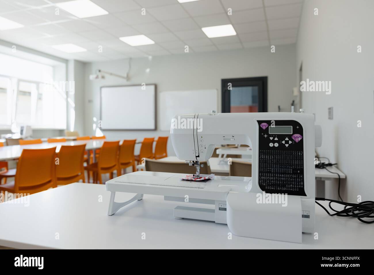 Modern sewing machine in a bright classroom ready for creative projects and learning Stock Photo