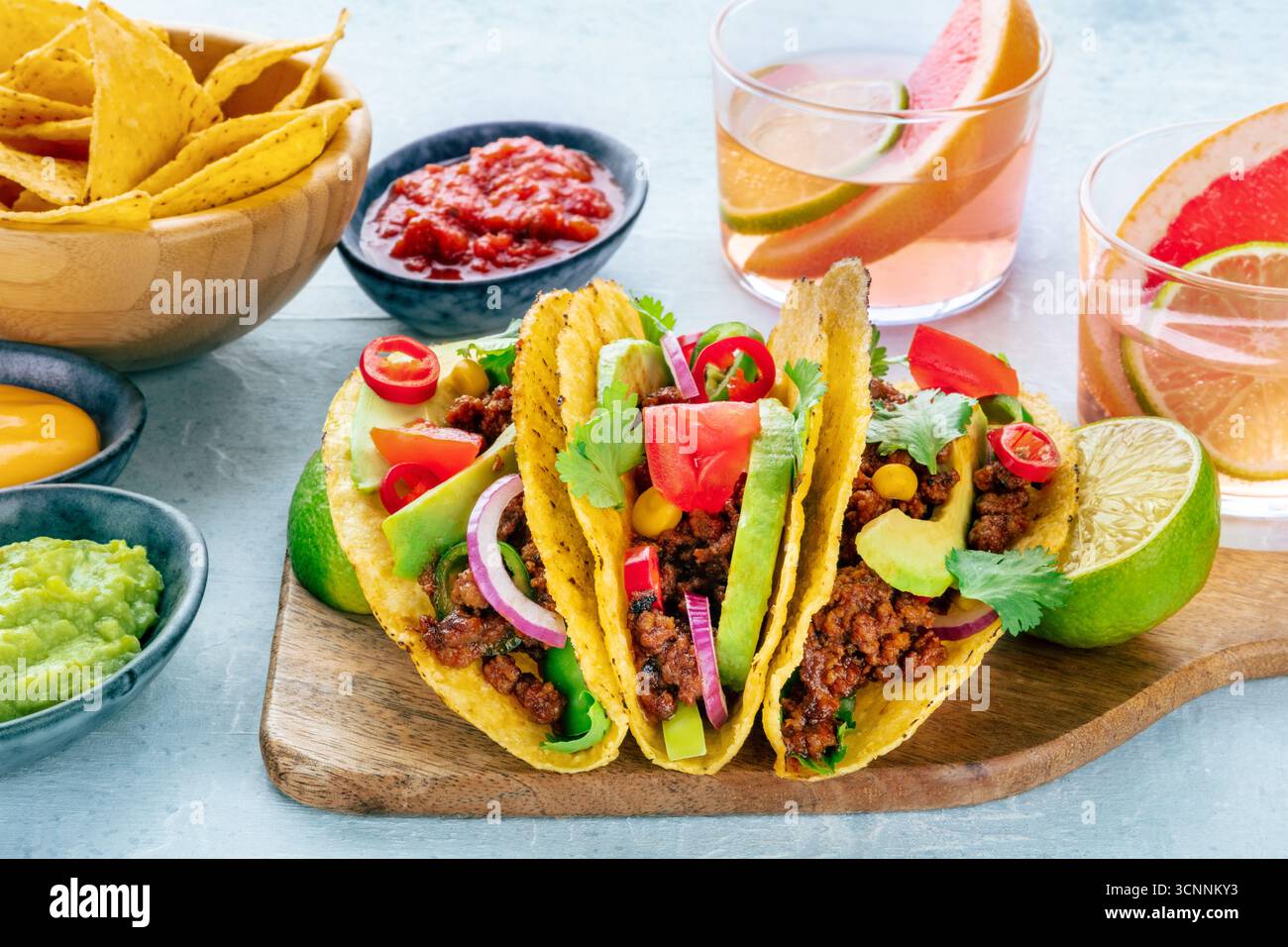 Tacos with meat and vegetables, with Paloma cocktails and nachos, Mexican food, with salsas and limes Stock Photo
