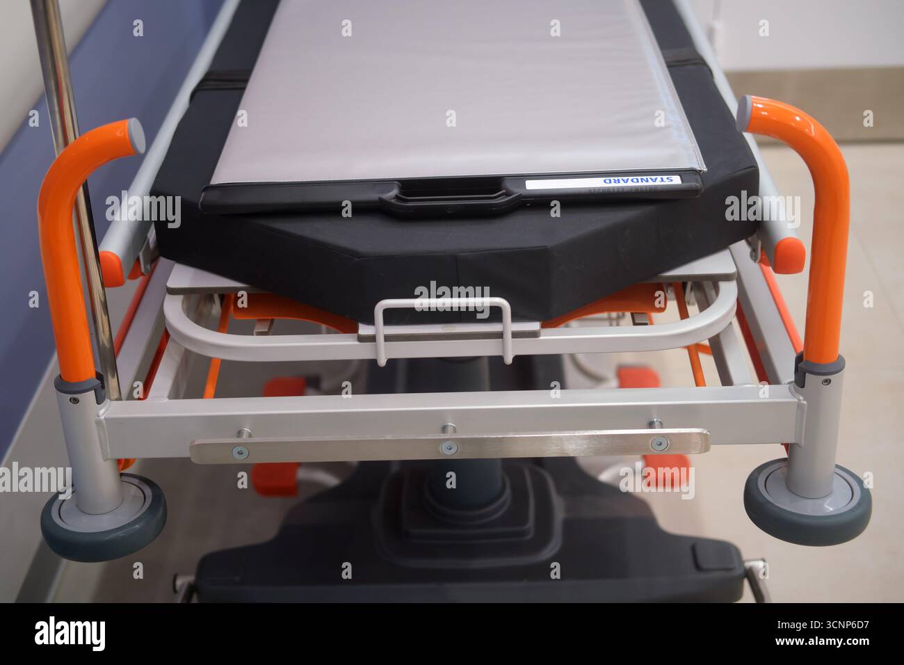 Empty medical emergency stretcher trolley with wheel and orange handle ...