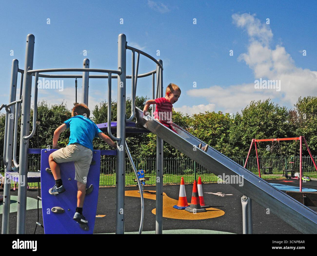 Two small boys playing on a slide. Stock Photo