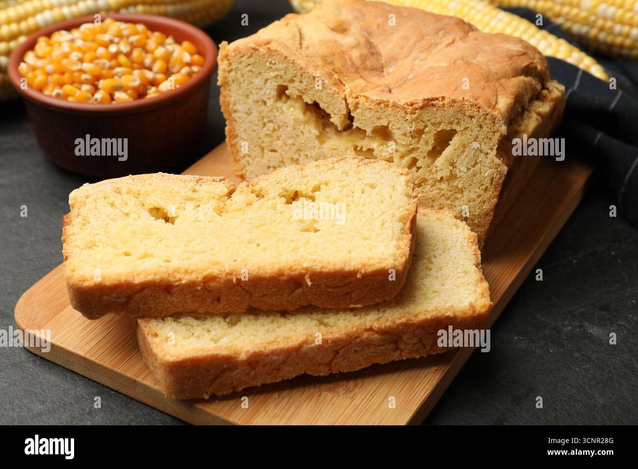 Freshly baked cornbread, cobs and seeds on black table, closeup Stock Photo