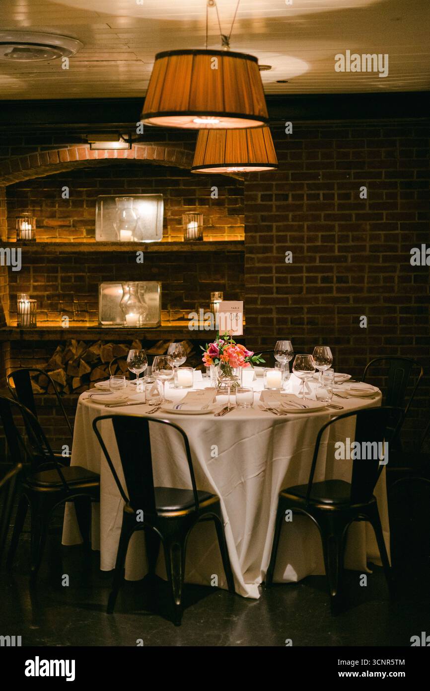 A round table elegantly set for dinner with flowers, candles, and fine ...