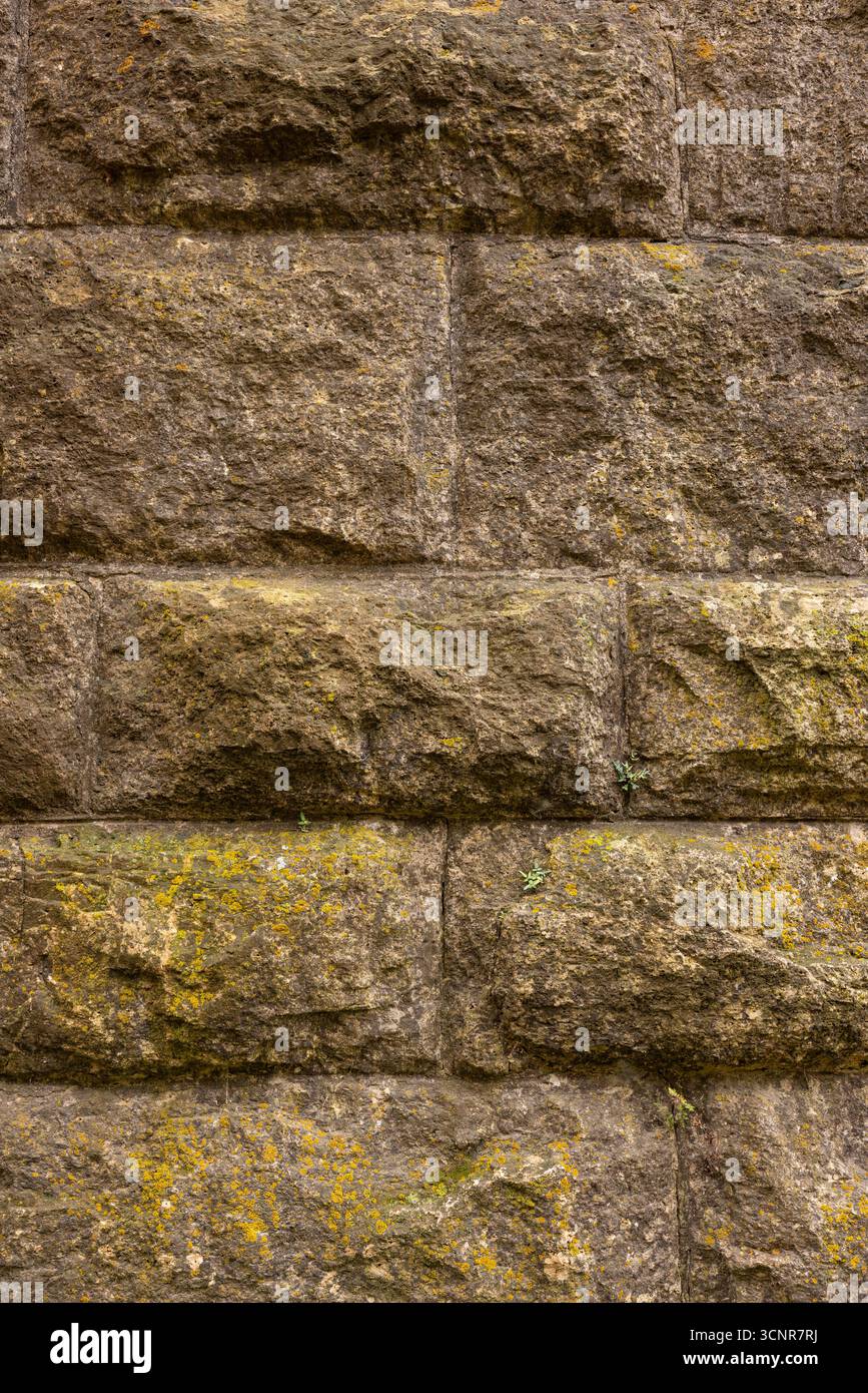An old stone block wall with a little moss growing on it. Stock Photo