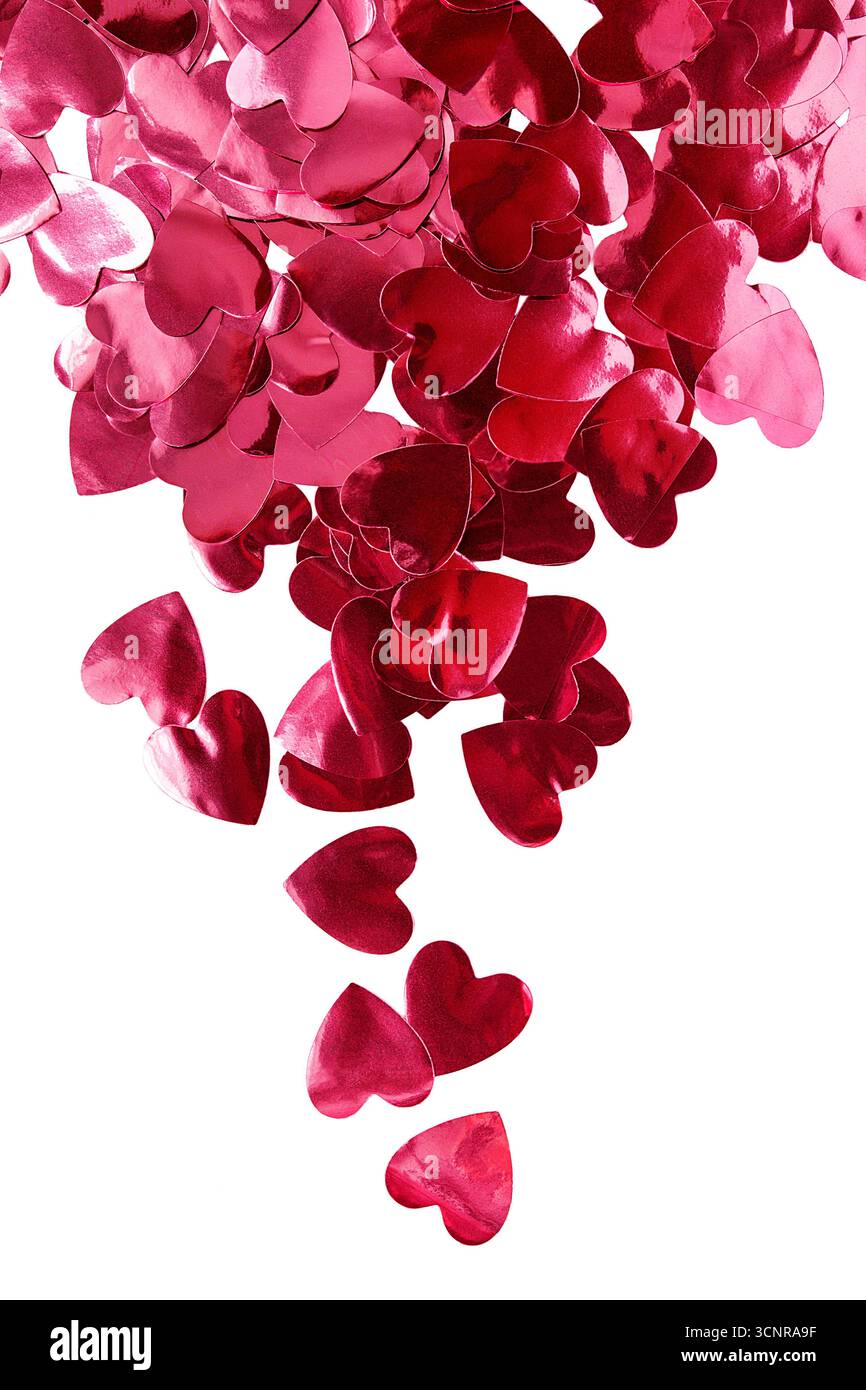 Lots of red metallic heart shaped confetti isolated on white background Stock Photo