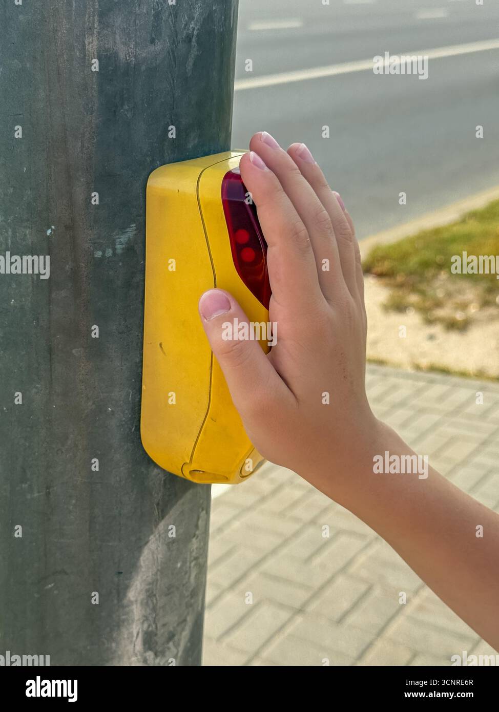 Close-up of a child’s hand pressing pedestrian crossing button on a traffic light pole for safe street crossing in the city - Smartphone Captured Stock Image