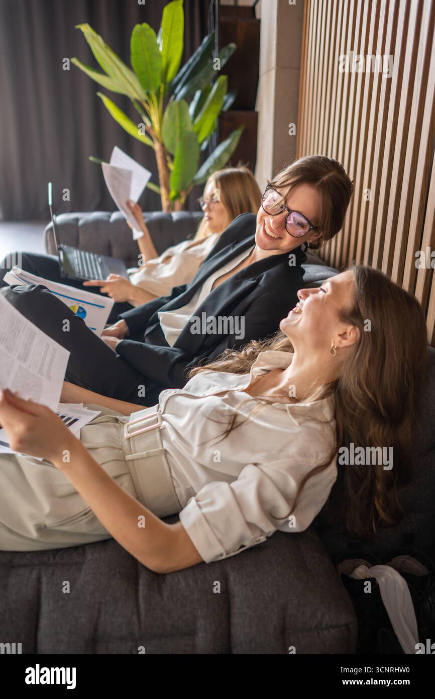 Intense Break Women in business attire resting on couch, enjoying a short office ...