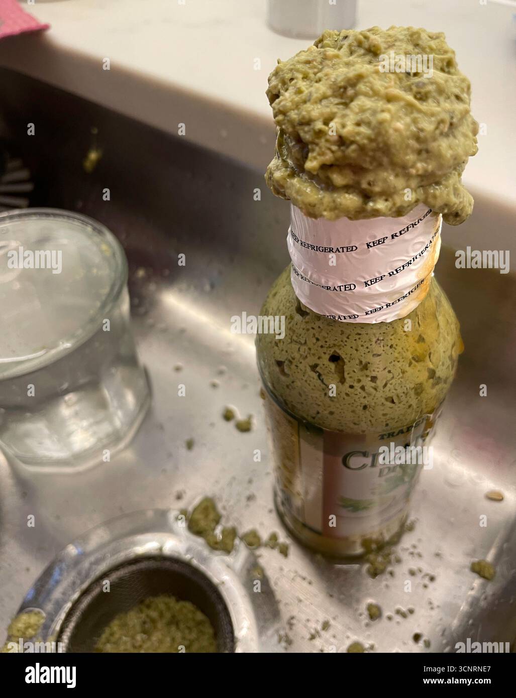 Spoiled salad dressing bottle in a kitchen sink when keep refrigerated instructions are ignored, 2025, United States - Smartphone Captured Stock Image