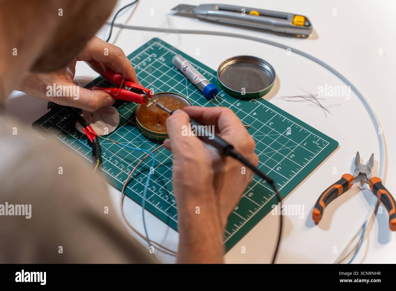 Hands working on electronic experiment with wires and soldering tools Stock Photo
