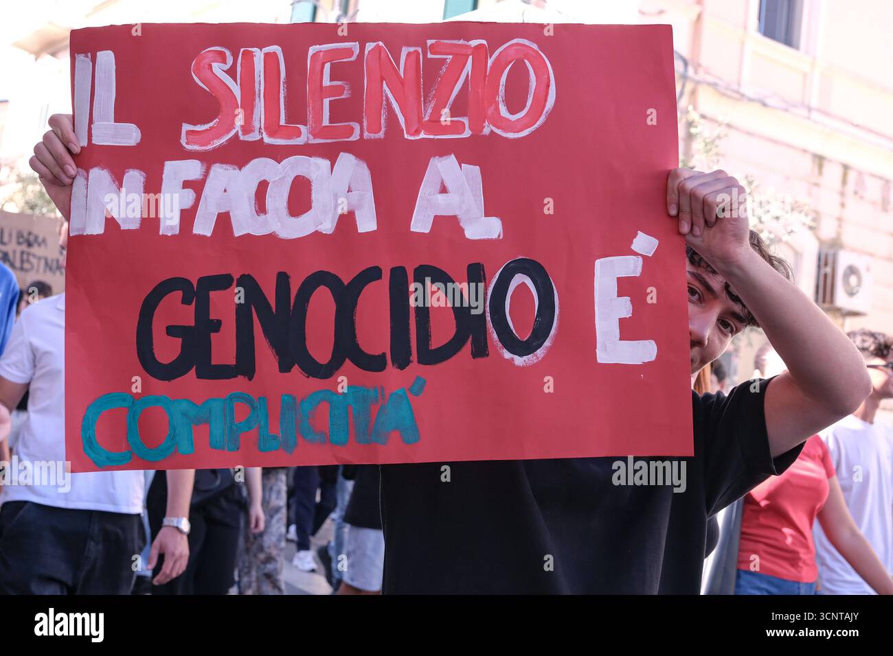 A boy holding a sign that reads ‘Silence in the face of genocide is ...