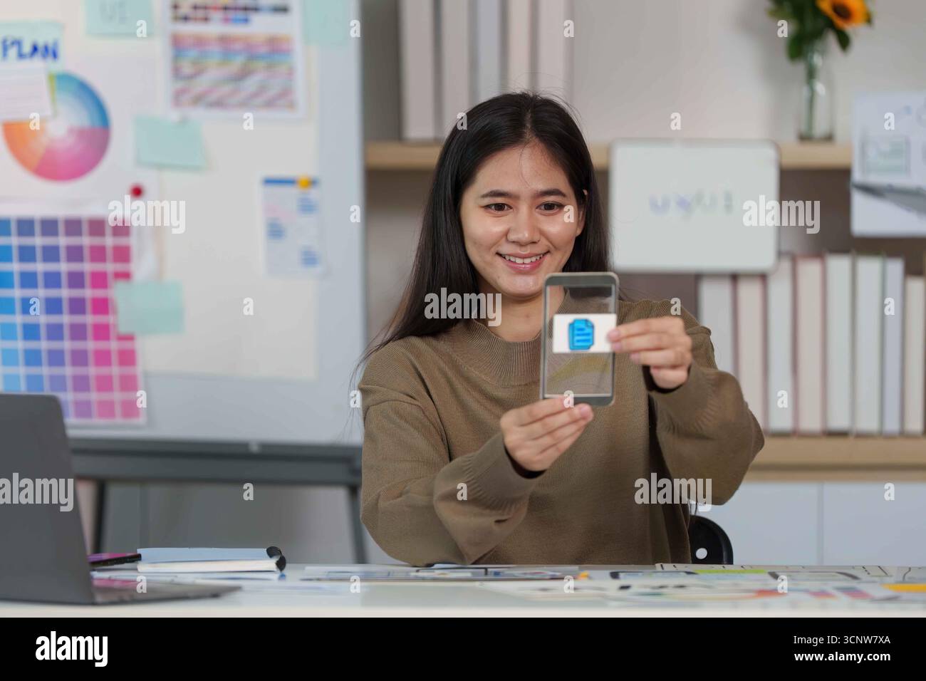 Smiling Designer Showcasing Mobile App Interface on Smartphone. Stock Photo