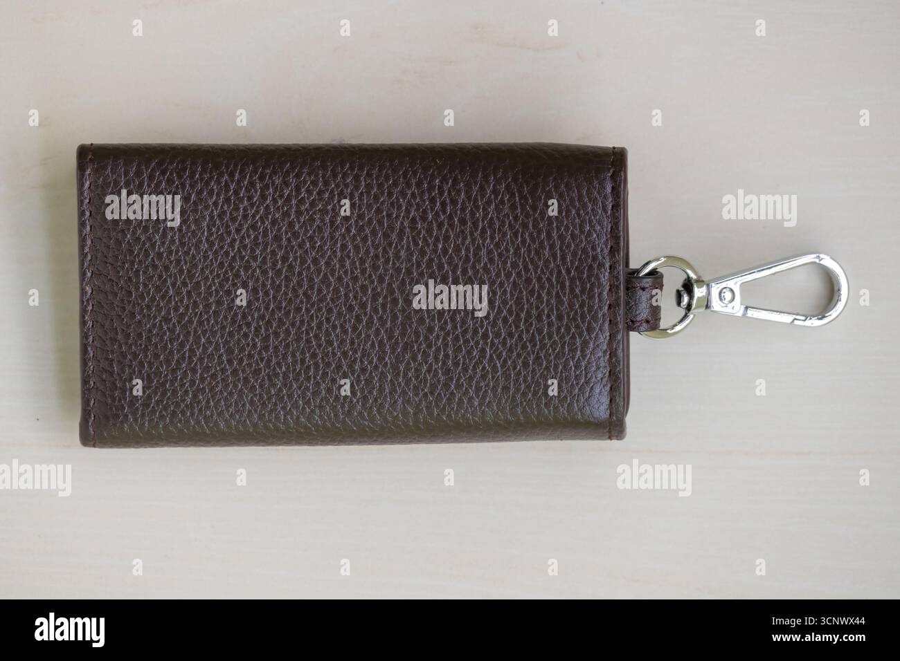 Stylish leather key holder on a light brown background. Stock Photo
