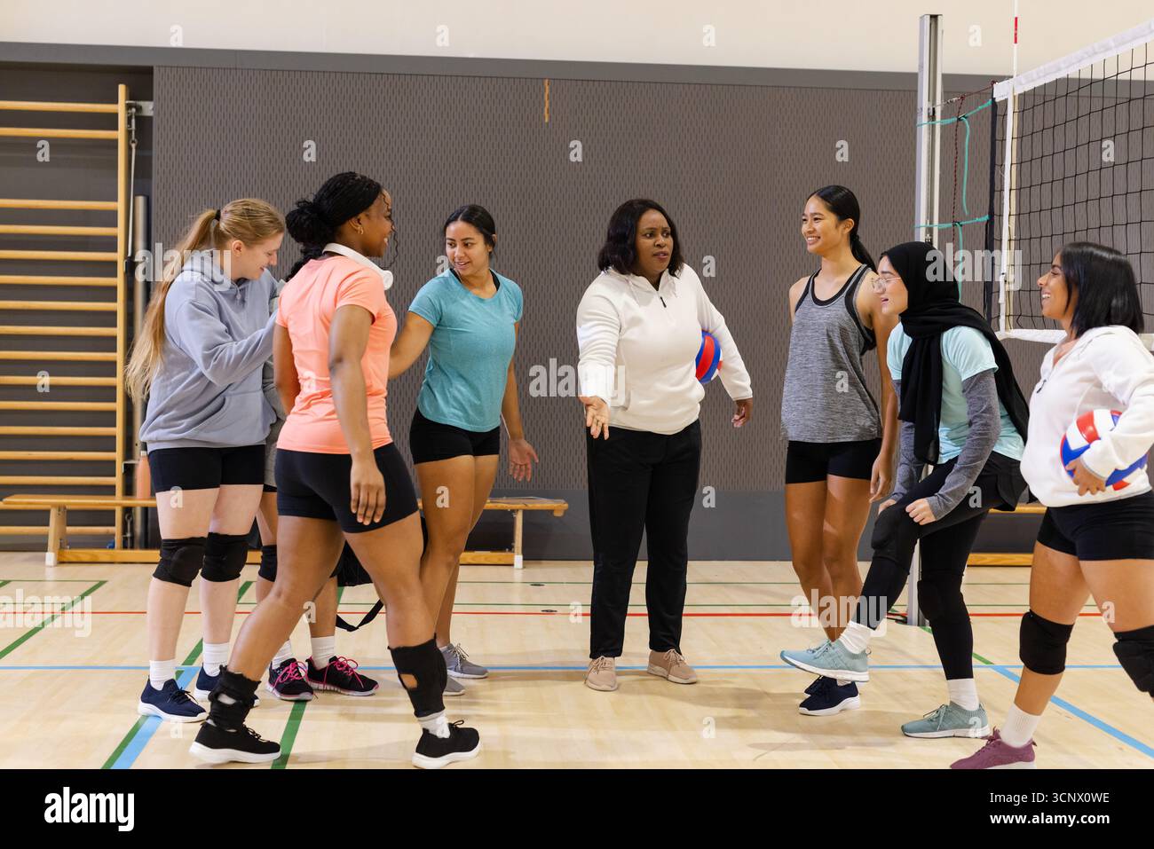 Female volleyball coach practicing with players at court Stock