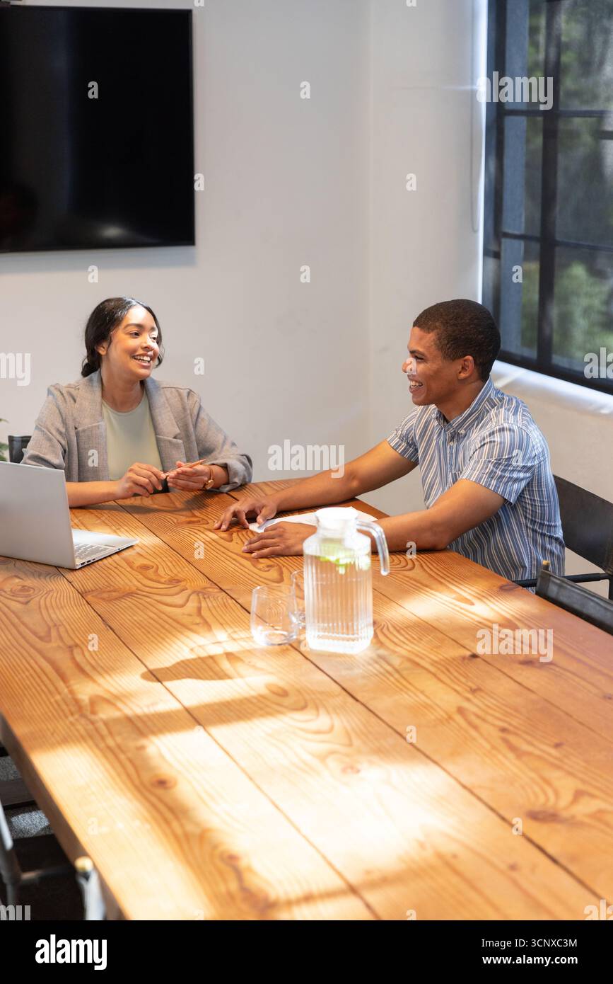 African american colleagues sitting at conference table discussing project with laptop, pitcher Stock Photo
