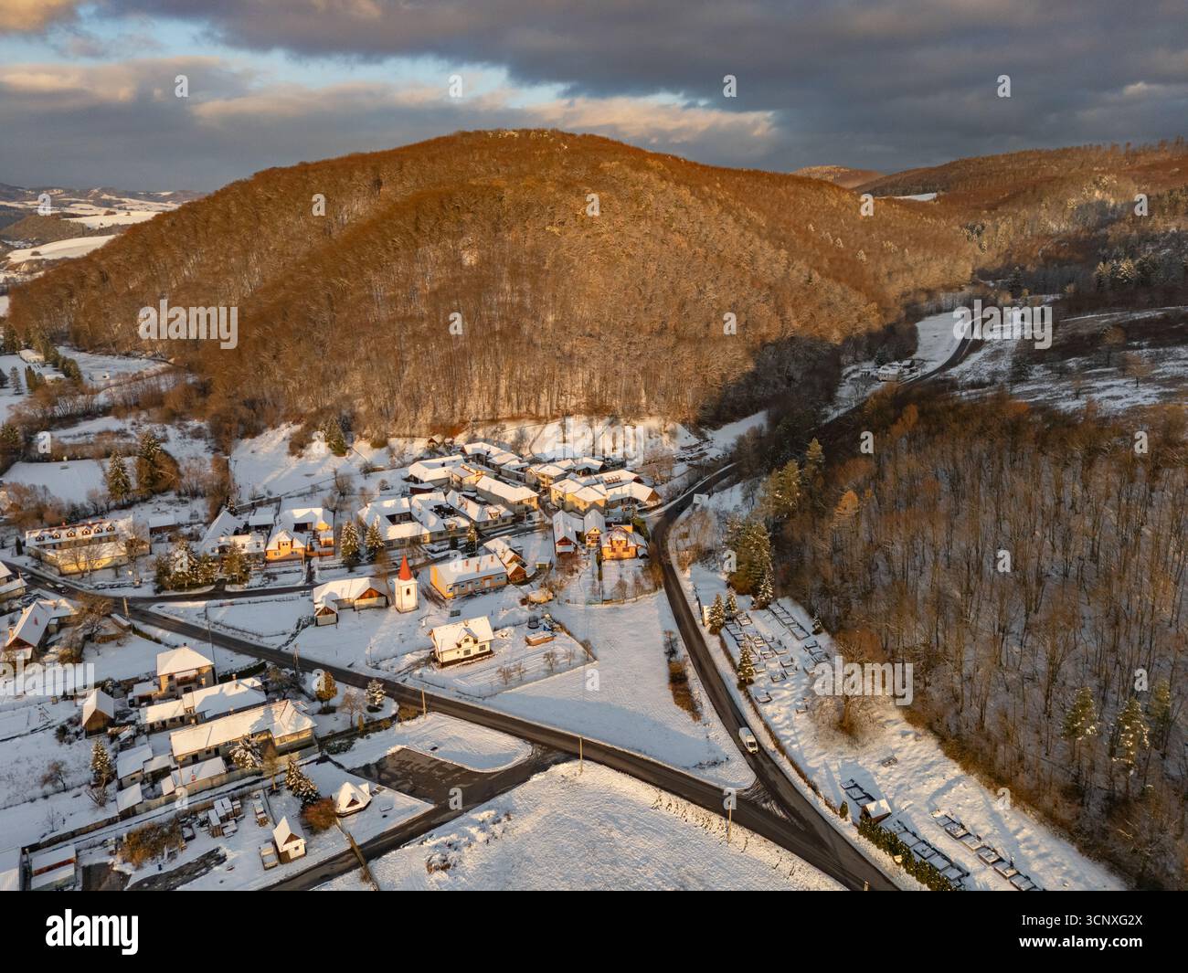 Aerial view of a snow-covered village nestled at the base of wooded ...