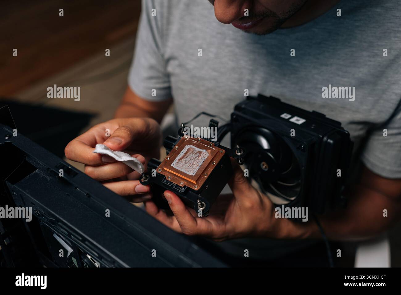 Precise computer maintenance involving cleaning processor cooling system, wiping delicate electronic components with white microfiber cloth for peak Stock Photo