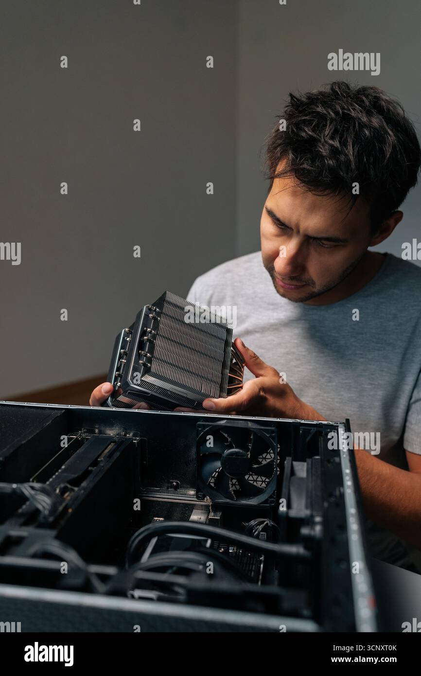 Vertical portrait of focused computer technician installing cooling radiator, carefully positioning computer hardware component during precision Stock Photo