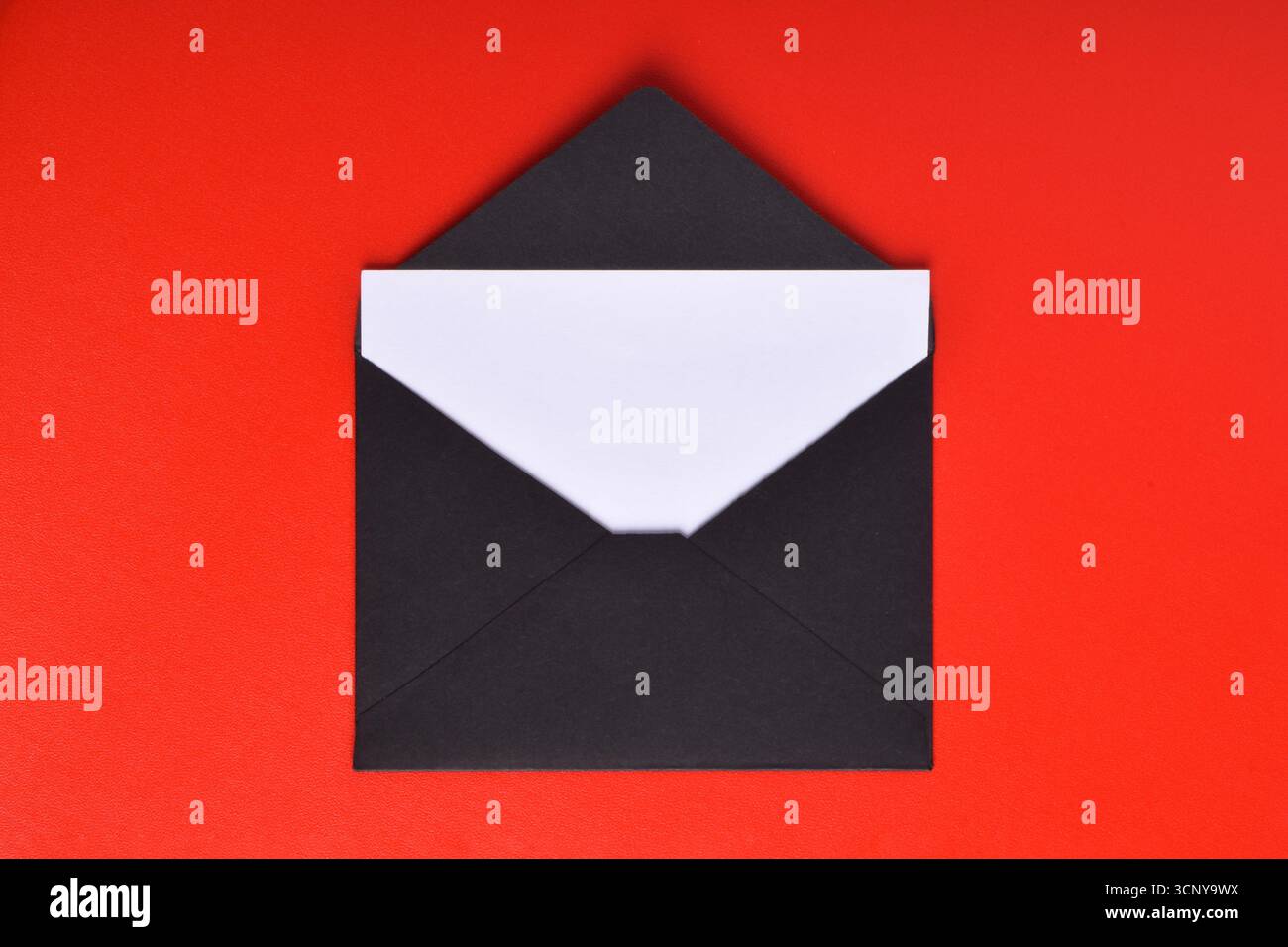 Opened black paper envelope with paper sheet isolated on red background Stock Photo
