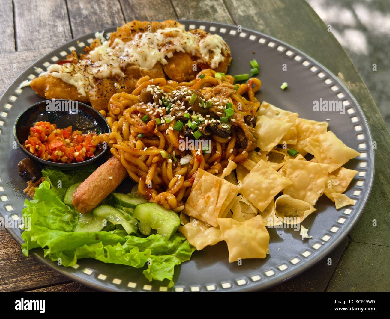 Chicken katsu noodles with sausage, mushroom, lettuce, wonton skin, and chili toppings Stock Photo