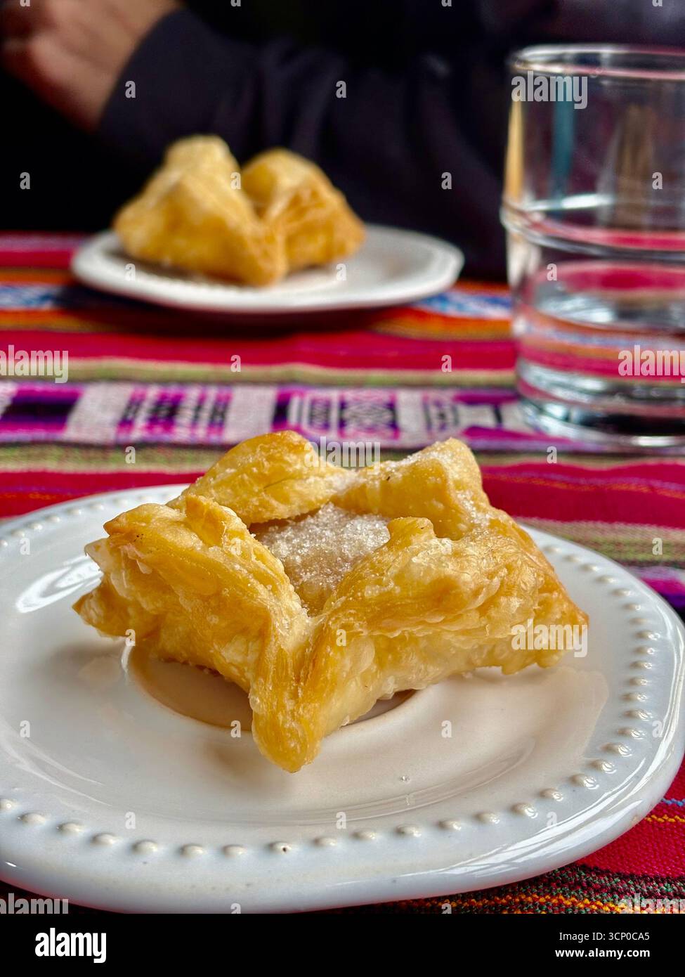 Traditional Argentine fried pastry served on a white plate with a colorful woven tablecloth background in Buenos Aires, Argentina. - Smartphone Captured Stock Image
