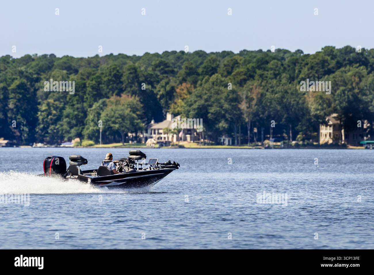 Boater on fishing bass boat enjoy summer day fishing on freshwater lake. Stock Photo