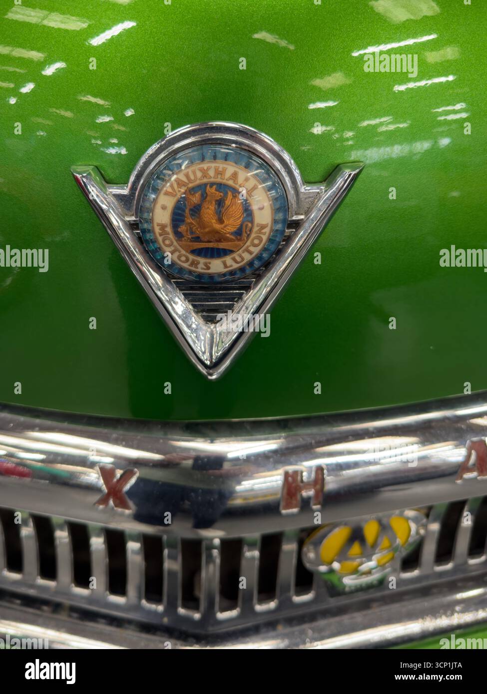 Close-up of the boonet badge emblem of a vintage green vauxhall with chrome details and green metallic paint - Smartphone Captured Stock Image