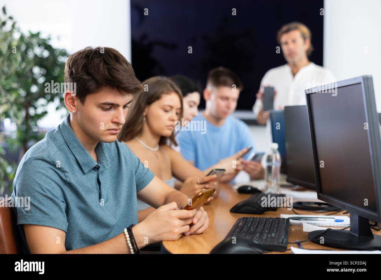Focused young student using smartphone while studying in computer workshop Stock Photo