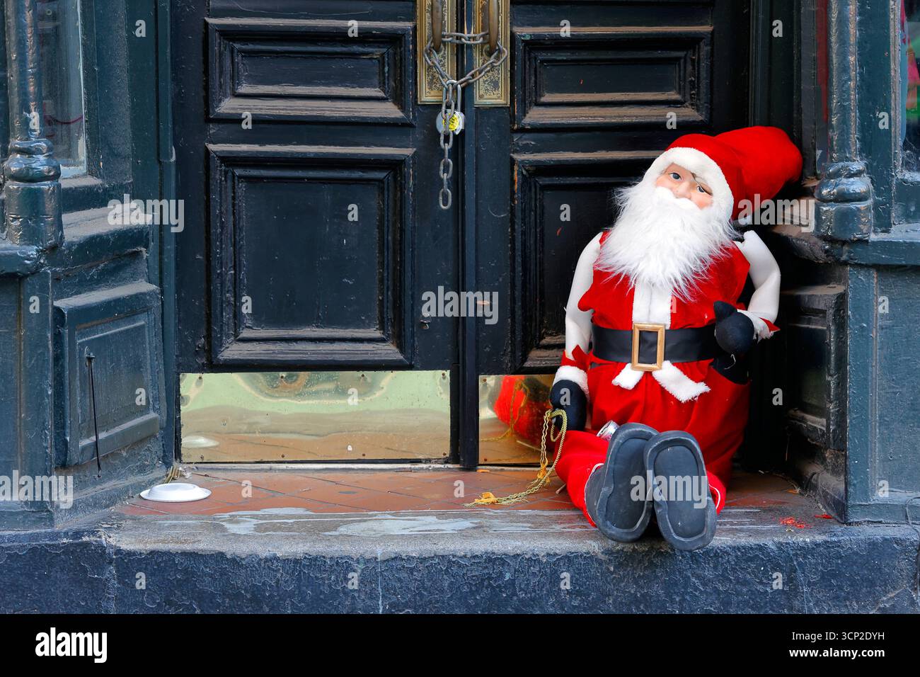A Santa Claus dall sitting on the steps of a doorway. Stock Photo