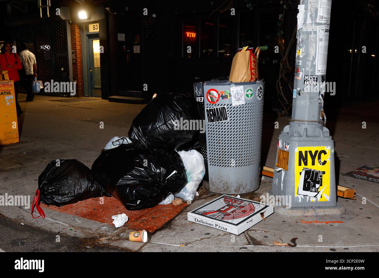 Garbage and trash piled near a NYC sidewalk litter basket in Manhattan's East Village neighborhood. Stock Photo