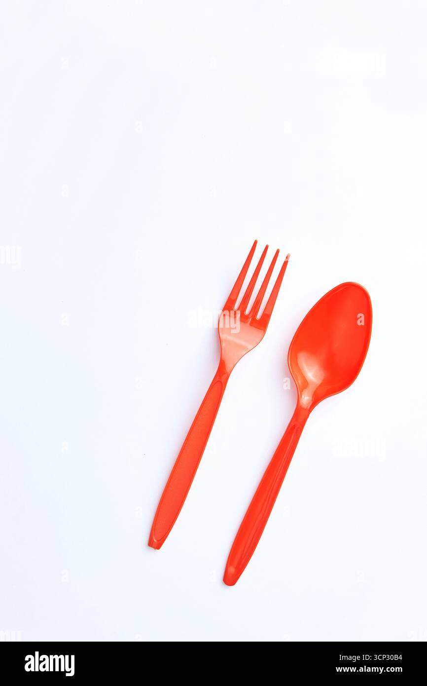 A red plastic fork and spoon placed side by side on a clean white background. Stock Photo
