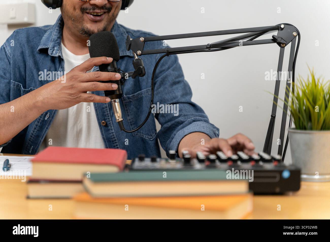 A young man broadcasting an online radio program from his home, representing modern careers, digital media, and internet communication. Stock Photo